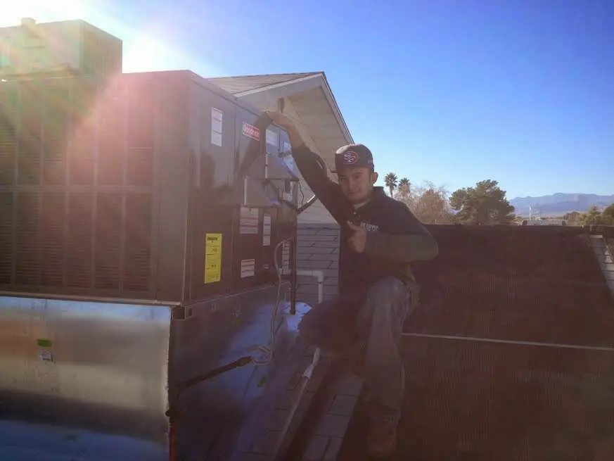 HVAC technician performing Air Duct Cleaning on a rooftop unit in Medford